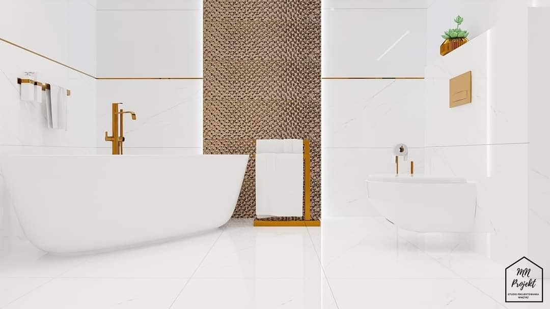 Wnętrze łazienki z białą wanną, bidetem i złotymi akcentami, w tym armaturą i dekoracyjną ścianą z fakturą, uzupełnione ręcznikami na złotym stojaku i rośliną w doniczce.
