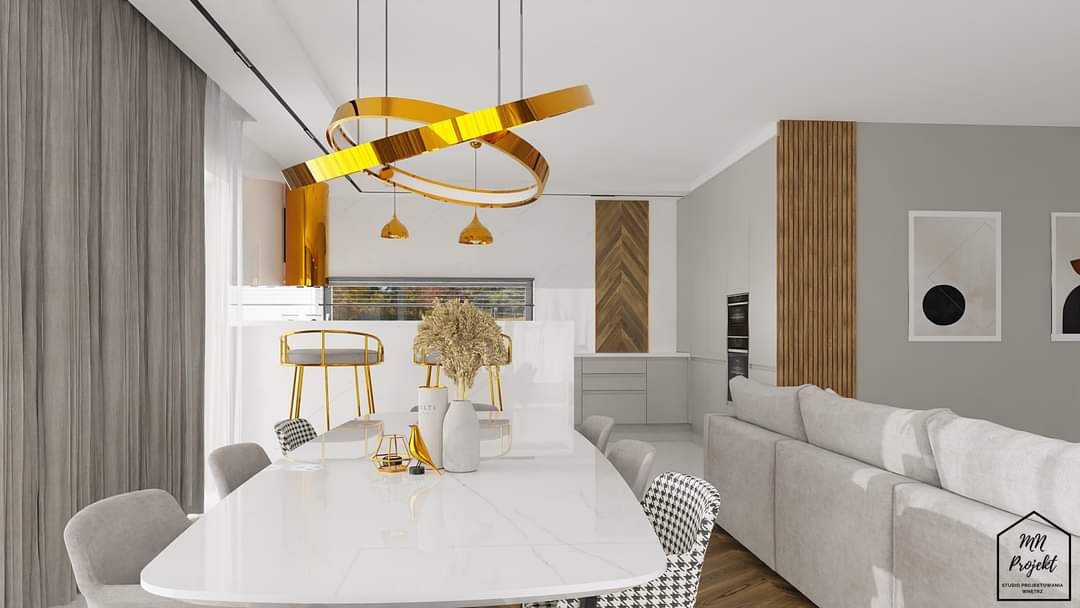 Jasne wnętrze jadalni z białym stołem marmurkowym, złotymi krzesłami barowymi i abstrakcyjną lampą pierścieniową. W tle widać drewniane panele ścienne i minimalistyczne grafiki.
