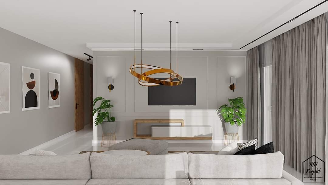 Nowoczesny salon z beżową sofą, złotą lampą wiszącą, telewizorem na ścianie, roślinami doniczkowymi i szarymi zasłonami.