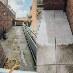 Czyszczenie ciśnieniowe płytek na tarasie: widoczna różnica między umytą a brudną powierzchnią, z żółtym wężem i myjką ciśnieniową w tle na tle ceglanych budynków.