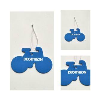 Niebieski, piankowy brelok w kształcie roweru z logo Decathlon, zawieszony na białym sznurku, na białym tle. Prezentacja produktu w trzech rozmiarach.