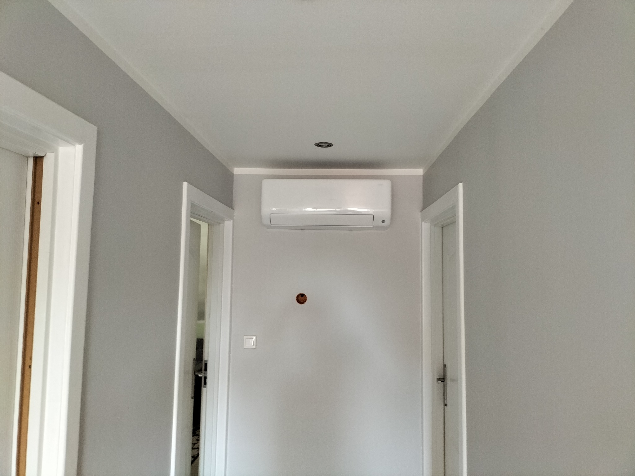 Klimatyzator zamontowany na ścianie w korytarzu domu w Czarnej Białostockiej, widoczne przygotowane miejsce na instalację elektryczną i włącznik światła.