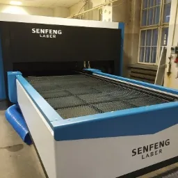 Maszyna laserowa Senfeng z niebieskimi akcentami, kratownica robocza wewnątrz, widoczne przewody wentylacyjne.