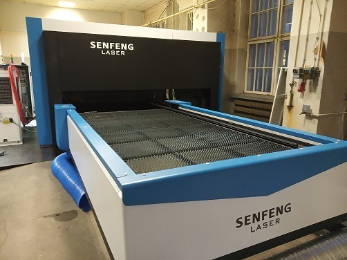 Maszyna laserowa Senfeng z niebieskimi akcentami, kratownica robocza wewnątrz, widoczne przewody wentylacyjne.