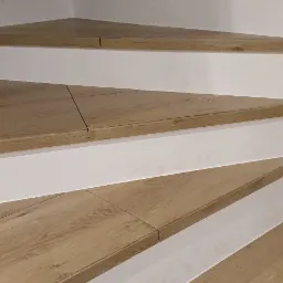 Drewnopodobne płytki na schodach z białymi podstopnicami, widok z dołu, widoczna fuga między płytkami.