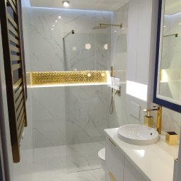 mak.bud.nowak - Elegancka łazienka z marmurowymi płytkami, złotymi akcentami i minimalistycznym wyposażeniem, oświetlona ledami.