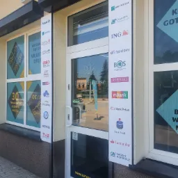 Fasada placówki finansowej w Libiążu z logo różnych banków i firm ubezpieczeniowych na tablicach informacyjnych obok wejścia.