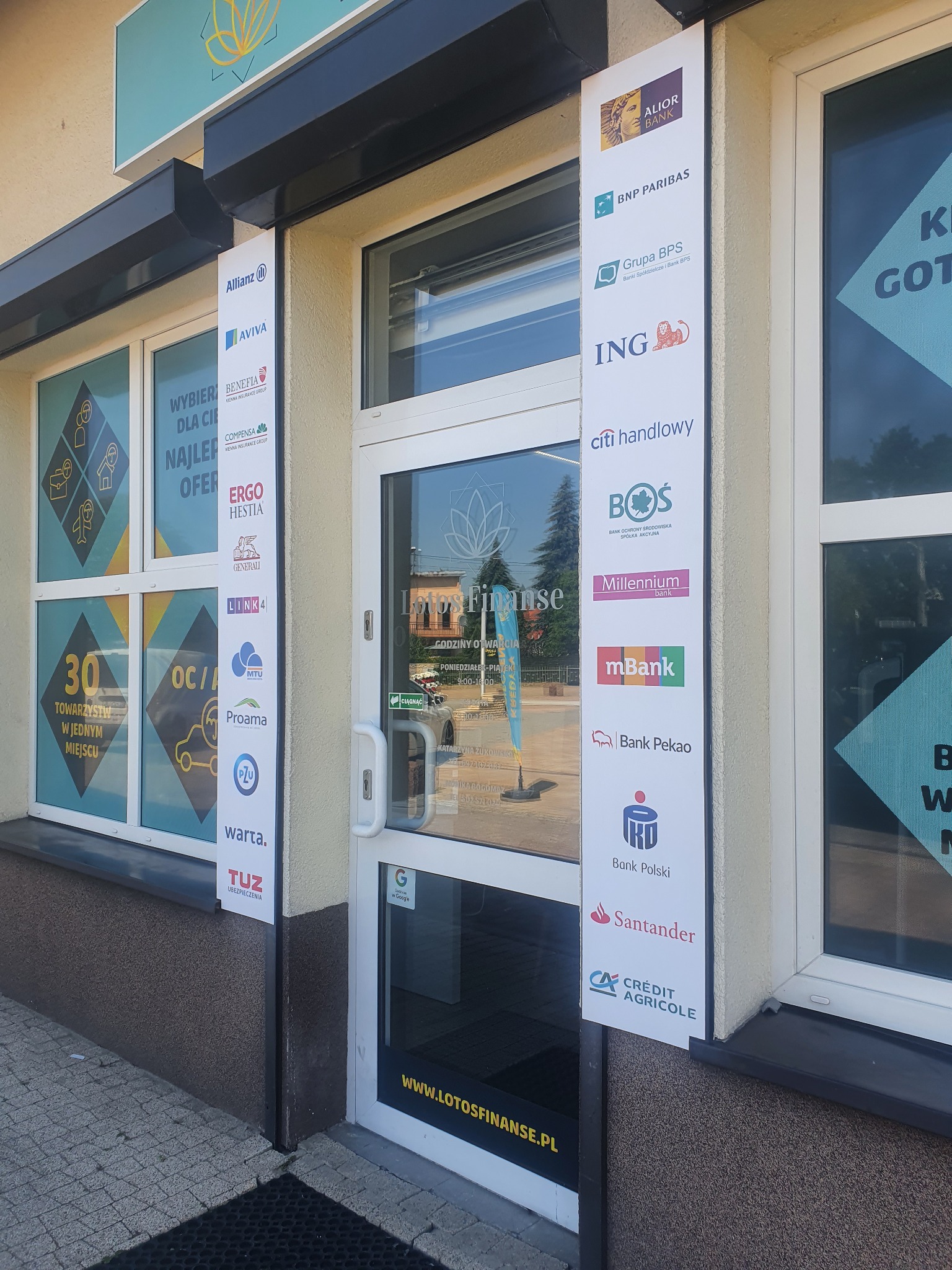 Fasada placówki finansowej w Libiążu z logo różnych banków i firm ubezpieczeniowych na tablicach informacyjnych obok wejścia.