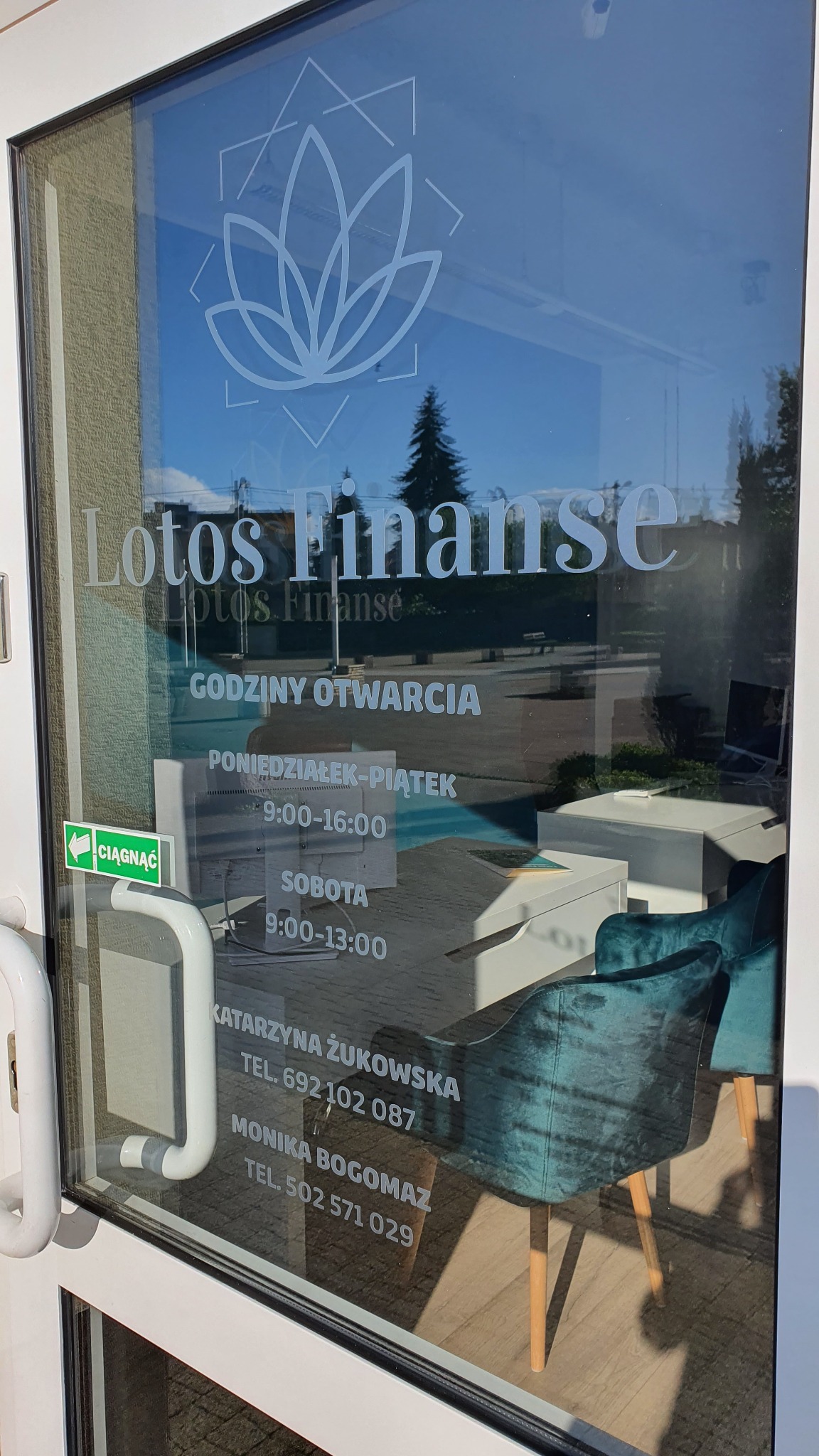 Przeszklone drzwi wejściowe do biura Lotos Finanse z naklejonym logo i godzinami otwarcia, widoczne wnętrze z krzesłami i biurkami.
