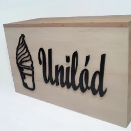 Drewniana lada z logo lodziarni Unilód, czarne, przestrzenne litery i grafika lodów na jasnym tle drewna.
