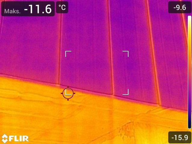 Termogram ściany z widocznymi różnicami temperatur, wskazujący na potencjalne problemy z izolacją. Kolory od fioletu (zimno) do żółto-pomarańczowego (ciepło).