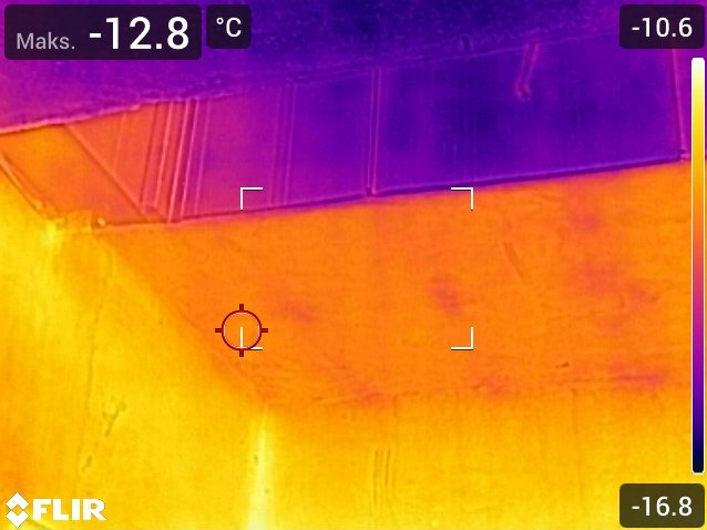 Termowizja dachu budynku, ukazująca rozkład temperatur w odcieniach fioletu, pomarańczy i żółci. Widoczne wartości temperatur w stopniach Celsjusza.