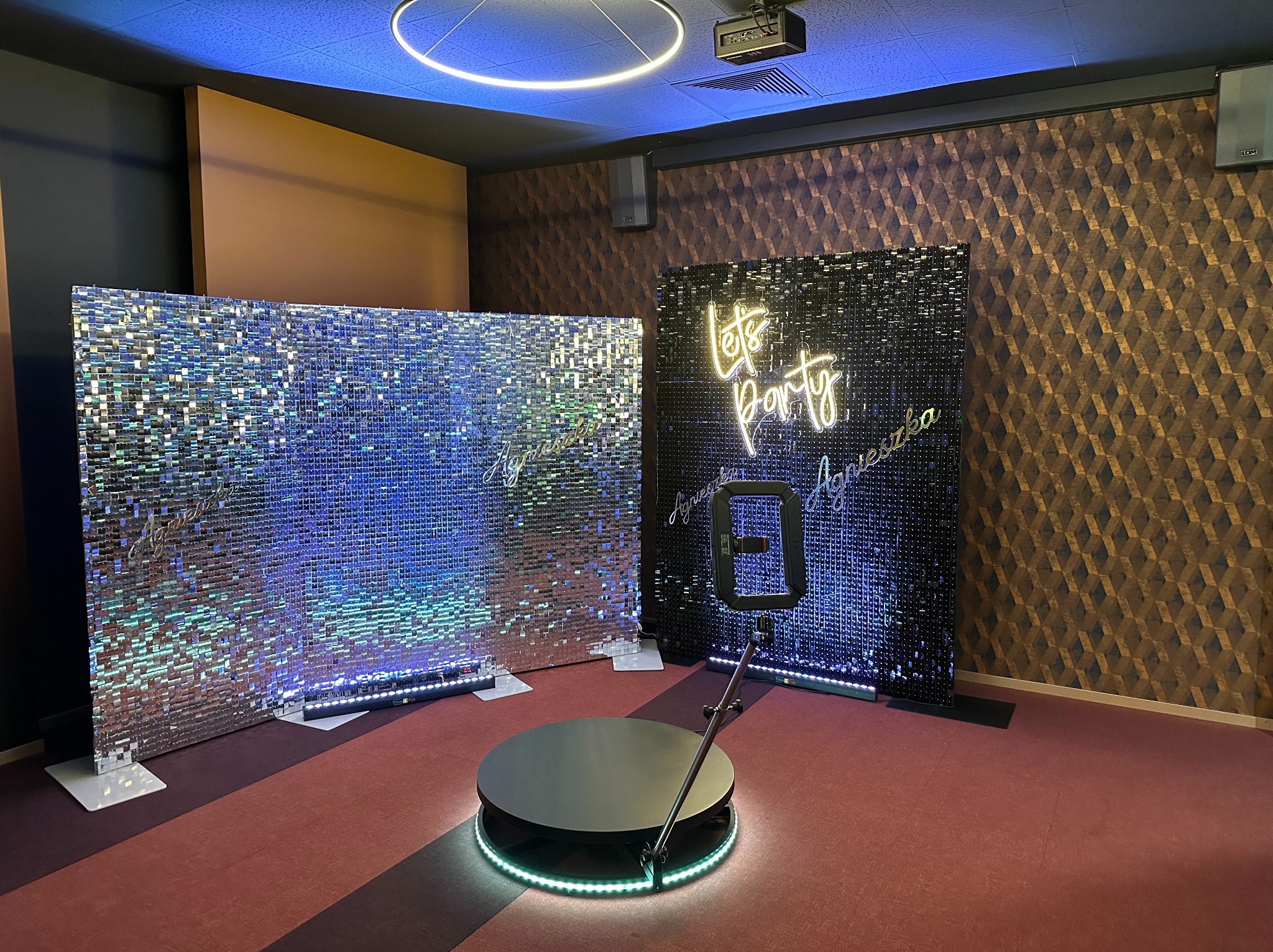 Wnętrze z obrotową platformą 360 stopni otoczoną LED, dwoma błyszczącymi ściankami, jedna srebrna, druga czarna z neonowym napisem 'Let's Party', gotowe do obsługi sesji zdjęciowej w Radomiu.