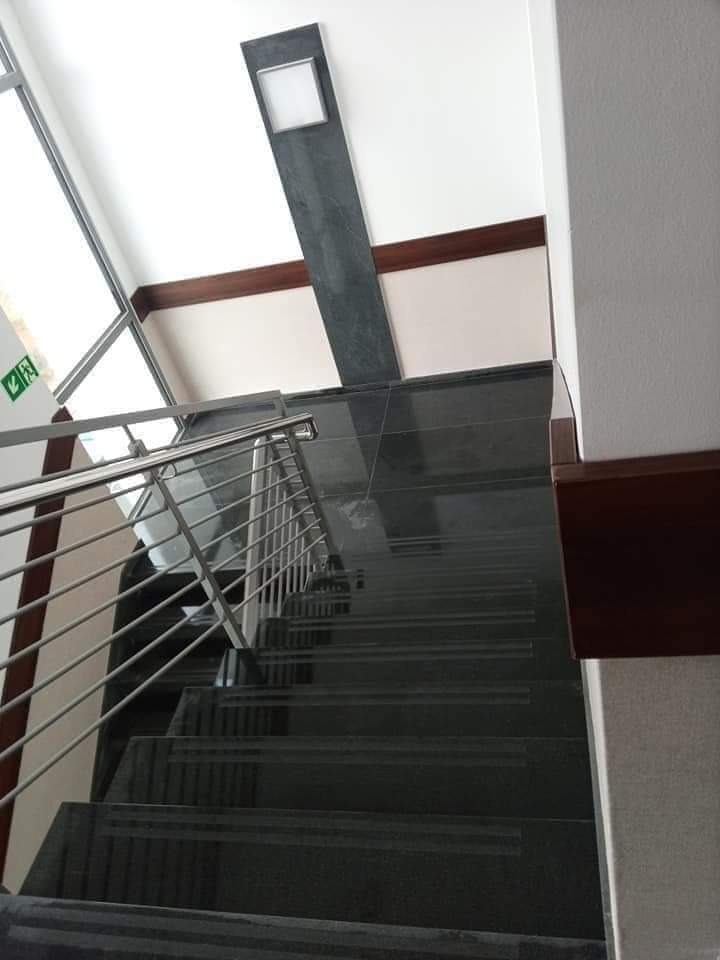 Schody wewnętrzne wyłożone ciemnym gresem z metalową balustradą i oknem na półpiętrze, widok z góry.