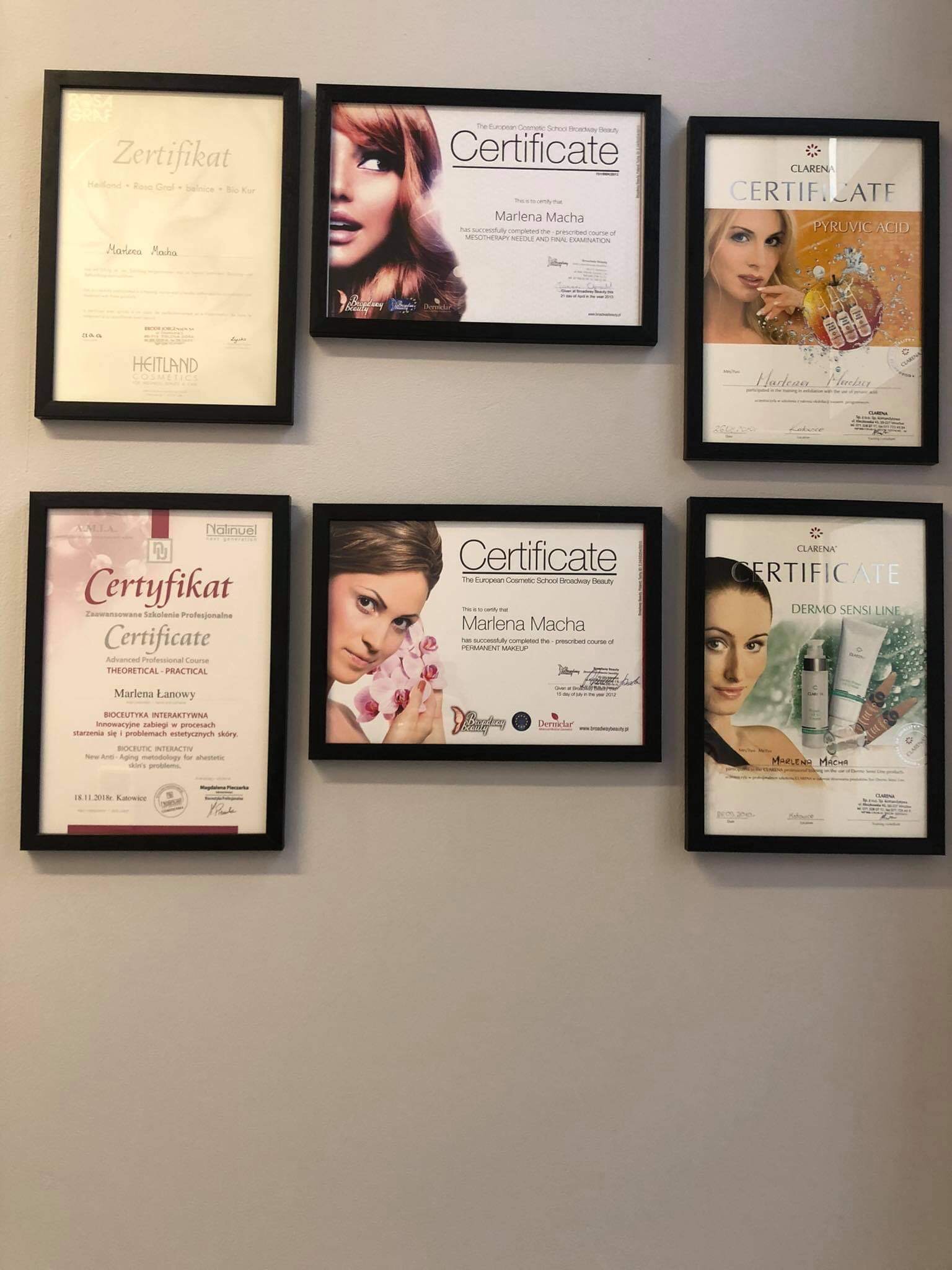 Ściana z sześcioma oprawionymi certyfikatami i dyplomami ukończenia szkoleń kosmetycznych i medycyny estetycznej, niektóre z wizerunkami modelek i produktami kosmetycznymi.