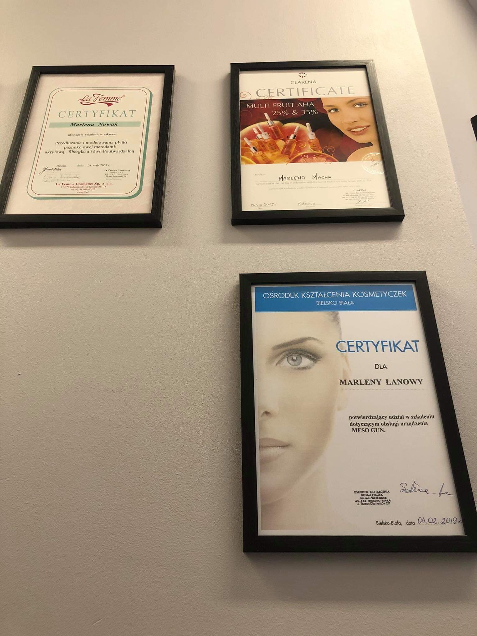 Trzy certyfikaty w czarnych ramkach wiszące na ścianie: jeden dotyczący przedłużania paznokci, drugi o produktach Multi Fruit AHA, trzeci o szkoleniu z obsługi urządzenia Meso Gun.