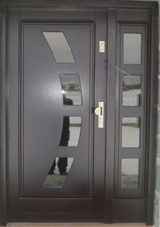 Ciemnobrązowe drzwi wejściowe z asymetrycznymi, ukośnymi przeszkleniami i bocznym panelem z czterema kwadratowymi szybami, prezentowane w świetle dziennym.