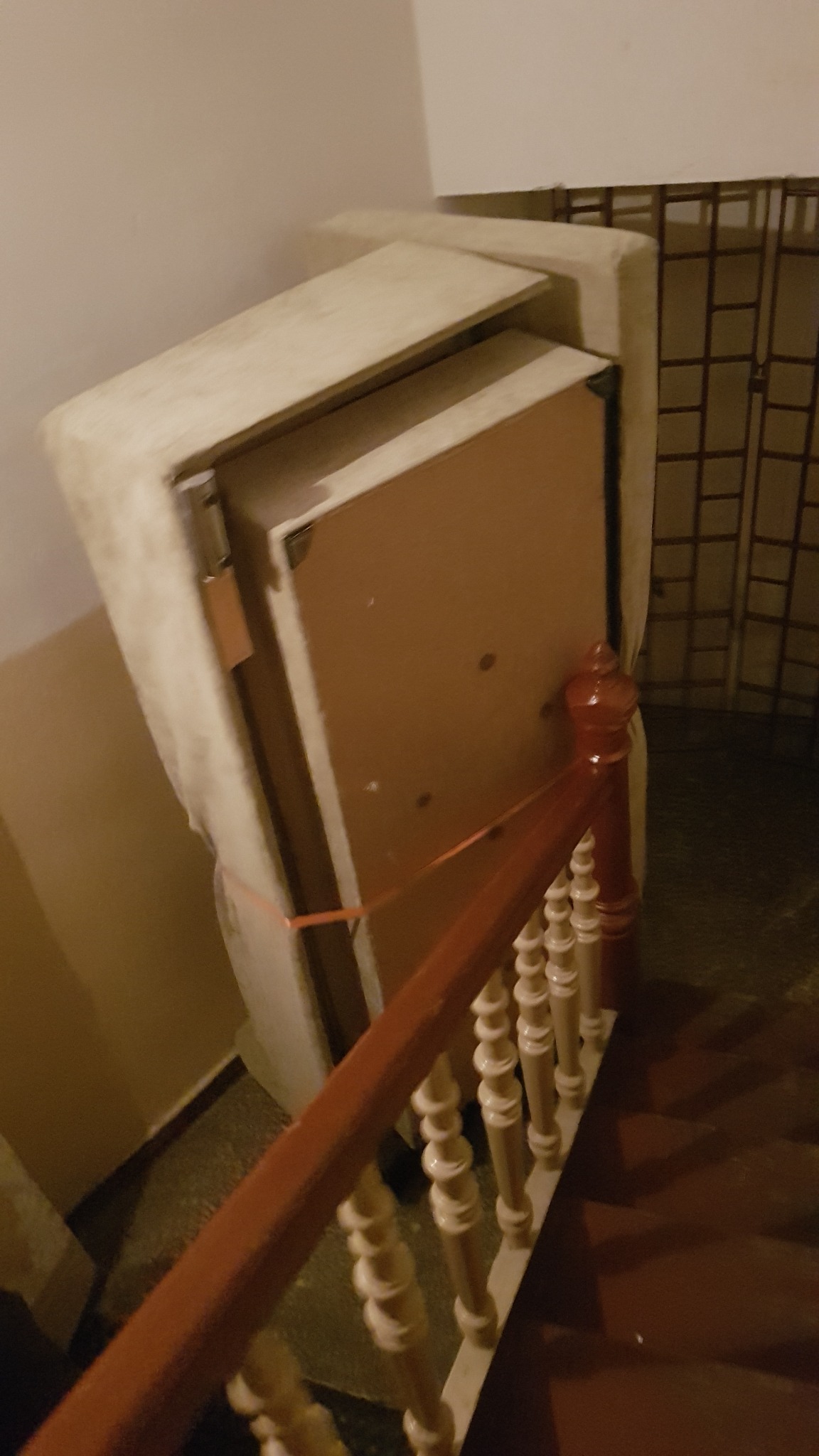 Mebel zabezpieczony folią i taśmą, transportowany po schodach z ozdobną balustradą.