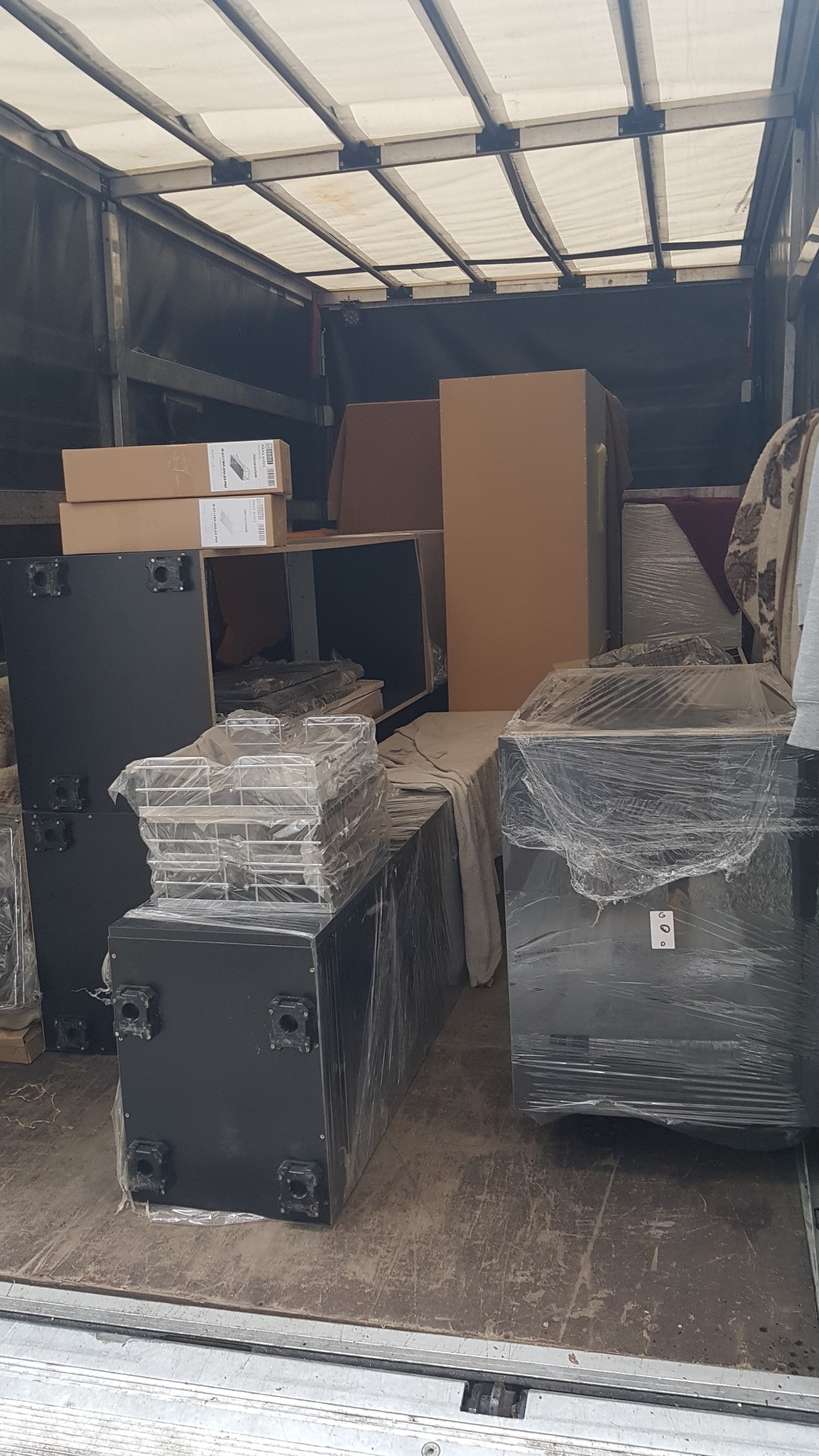 Wnętrze furgonetki załadowane meblami i przedmiotami zabezpieczonymi folią stretch, gotowymi do transportu.