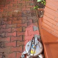 Czyszczenie kostki brukowej za pomocą okrągłej myjki ciśnieniowej; widoczny efekt różnicy czyszczonej i zabrudzonej powierzchni.