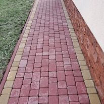 Czerwono-żółta kostka brukowa ułożona wzdłuż ściany budynku z cegły, widok z góry.