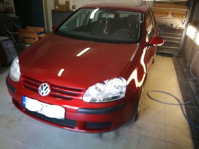Czerwony Volkswagen Golf po renowacji lakieru we Wrocławiu, widoczny w warsztacie z oświetleniem halogenowym.