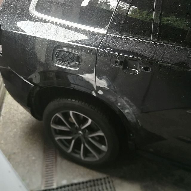 Częściowo zeszlifowany, czarny samochód kombi z uszkodzeniami na tylnych drzwiach i błotniku, przygotowany do lakierowania.