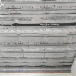 Metalowy stelaż sufitowy z folią paroizolacyjną Homeseal LDS FlexPlus, widok od dołu, przygotowany do montażu płyt gipsowo-kartonowych.