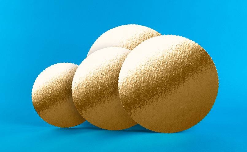 Cztery okrągłe, złote podkłady pod tort o falistych brzegach, ułożone jeden za drugim na turkusowym tle.