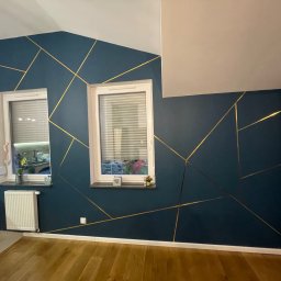 BestTiler - Ciemnoniebieska ściana z geometrycznym wzorem ze złotych linii, dwa okna z żaluzjami, drewniana podłoga, biały grzejnik i listwy przypodłogowe.