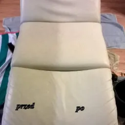 Tapicerowane krzesło z jasnej skóry, z widocznym efektem czyszczenia 'przed' i 'po', otoczone ręcznikami i wiadrem.