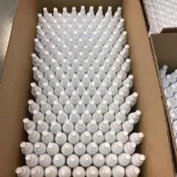 Kartonowe pudło wypełnione rzędami białych butelek z atomizerami, ułożonych równo i ciasno, gotowych do wysyłki.