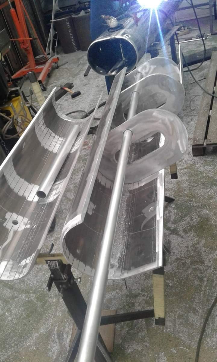 W trakcie spawania metalowej konstrukcji z elementów rurowych i blach, widoczne iskry i spawarka, obróbka metalu w warsztacie.