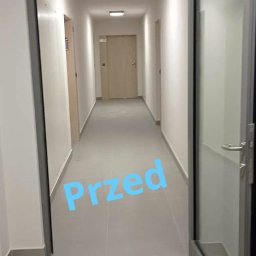 Kameleon Usługi Sprzątające i Ogrodnicze - Korytarz w budynku mieszkalnym przed czyszczeniem, widoczne jasne ściany, szara podłoga i kilka drzwi