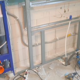 Andrzej Stachowski AMS - Stelaż podtynkowy Cersanit zamontowany w łazience w trakcie remontu, widoczne przewody i konstrukcja metalowa pod zabudowę