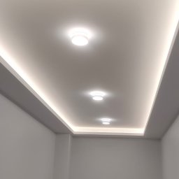 Andrzej Stachowski AMS - Nowoczesne oświetlenie sufitowe z trzema okrągłymi lampami i listwami LED w minimalistycznym wnętrzu z szarymi ścianami.