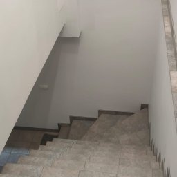 Andrzej Stachowski AMS - Schody wyłożone szarymi płytkami, widok z góry, z listwami przypodłogowymi z płytek.