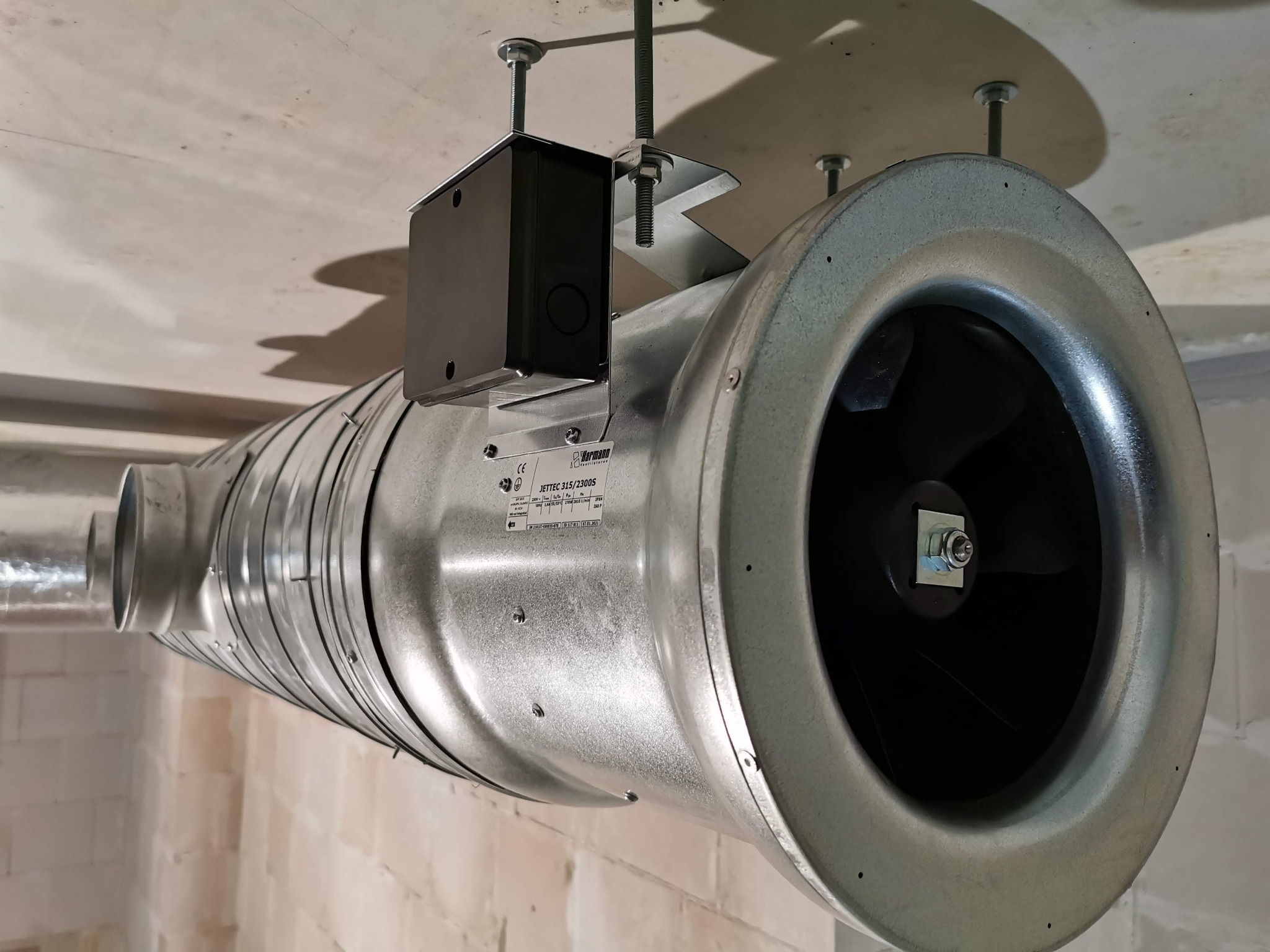 Zamontowany wentylator kanałowy z czarnym silnikiem, widoczne mocowania do sufitu z betonu komórkowego.