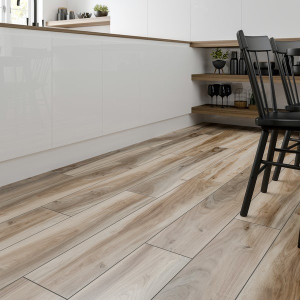 Jasnobrązowa podłoga imitująca drewno w kuchni z białymi, błyszczącymi szafkami i czarnymi krzesłami w tle.