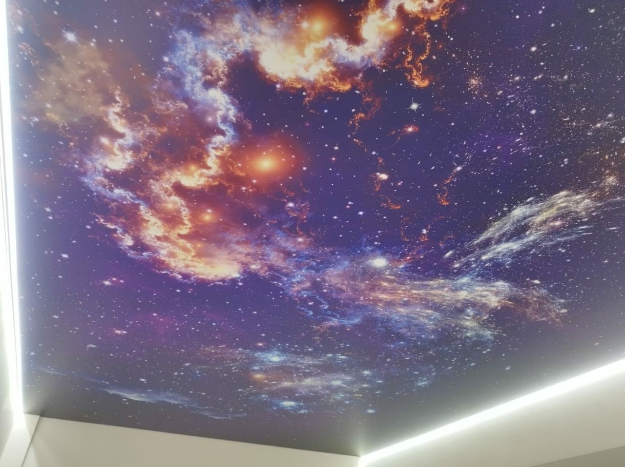 Niebiesko-fioletowy sufit z motywem kosmosu, przypominający galaktykę i gwiazdy, z oświetleniem LED wzdłuż krawędzi.