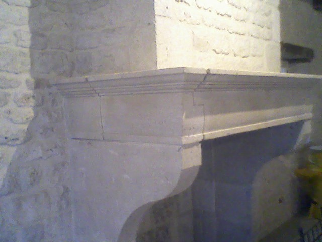 Kamienny kominek z dekoracyjnymi listwami w Sulejówku, wkomponowany w surową, kamienną ścianę. Widoczne detale architektoniczne i faktura kamienia.