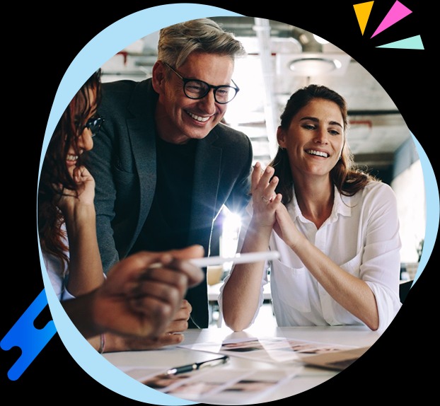 Zespół kreatywny w trakcie burzy mózgów nad projektami graficznymi, uśmiechnięci, z widocznymi szkicami i notatkami na stole.