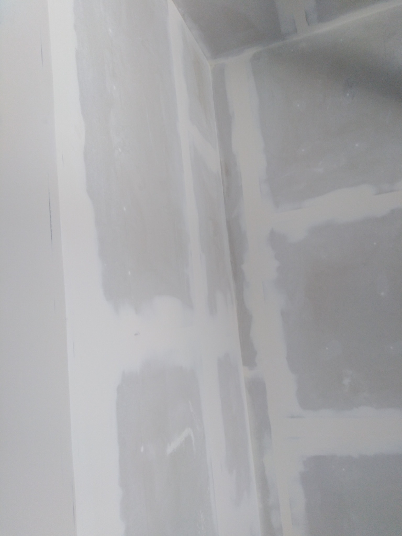 Wnętrze narożnika pomieszczenia z widocznymi łączeniami płyt pokrytymi masą szpachlową, przygotowanymi do dalszej obróbki.