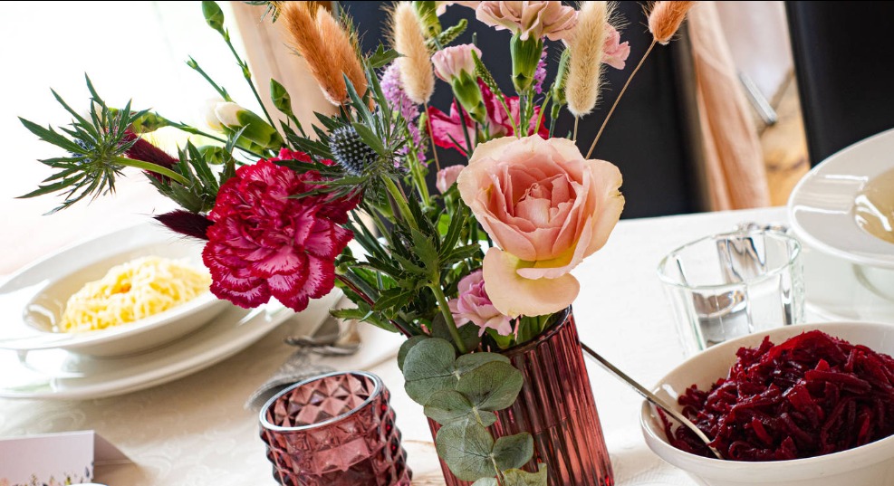 Dekoracja stołu z bukietem polnych kwiatów w prążkowanym wazonie i sałatką z buraków.