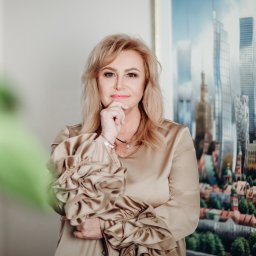 WARSO NIERUCHOMOŚCI - Portret kobiety w beżowej sukience z bufkami na tle obrazu przedstawiającego panoramę miasta z wysokimi budynkami i starymi kamienicami.