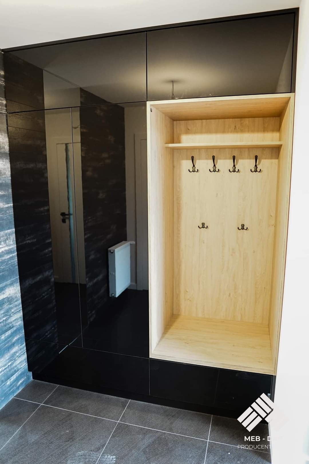 Nowoczesna szafa z lustrzanymi drzwiami i otwartą wnęką z jasnego drewna z wieszakami, widoczna w przedpokoju z szarą podłogą.