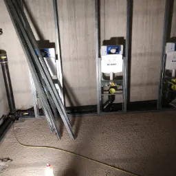 Montaż stelaży podtynkowych Geberit w łazience w trakcie remontu, widoczne rury kanalizacyjne i profile metalowe.