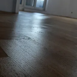 Świeżo ułożony, lakierowany parkiet w jodełkę, z widocznymi promieniami światła odbijającymi się od powierzchni.