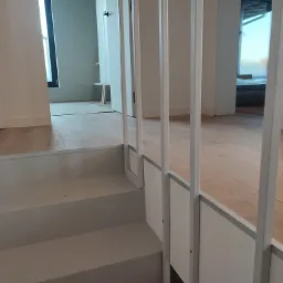 Nowoczesne schody wewnętrzne z białymi balustradami i drewnianą podłogą, widok z dołu, minimalistyczny design.