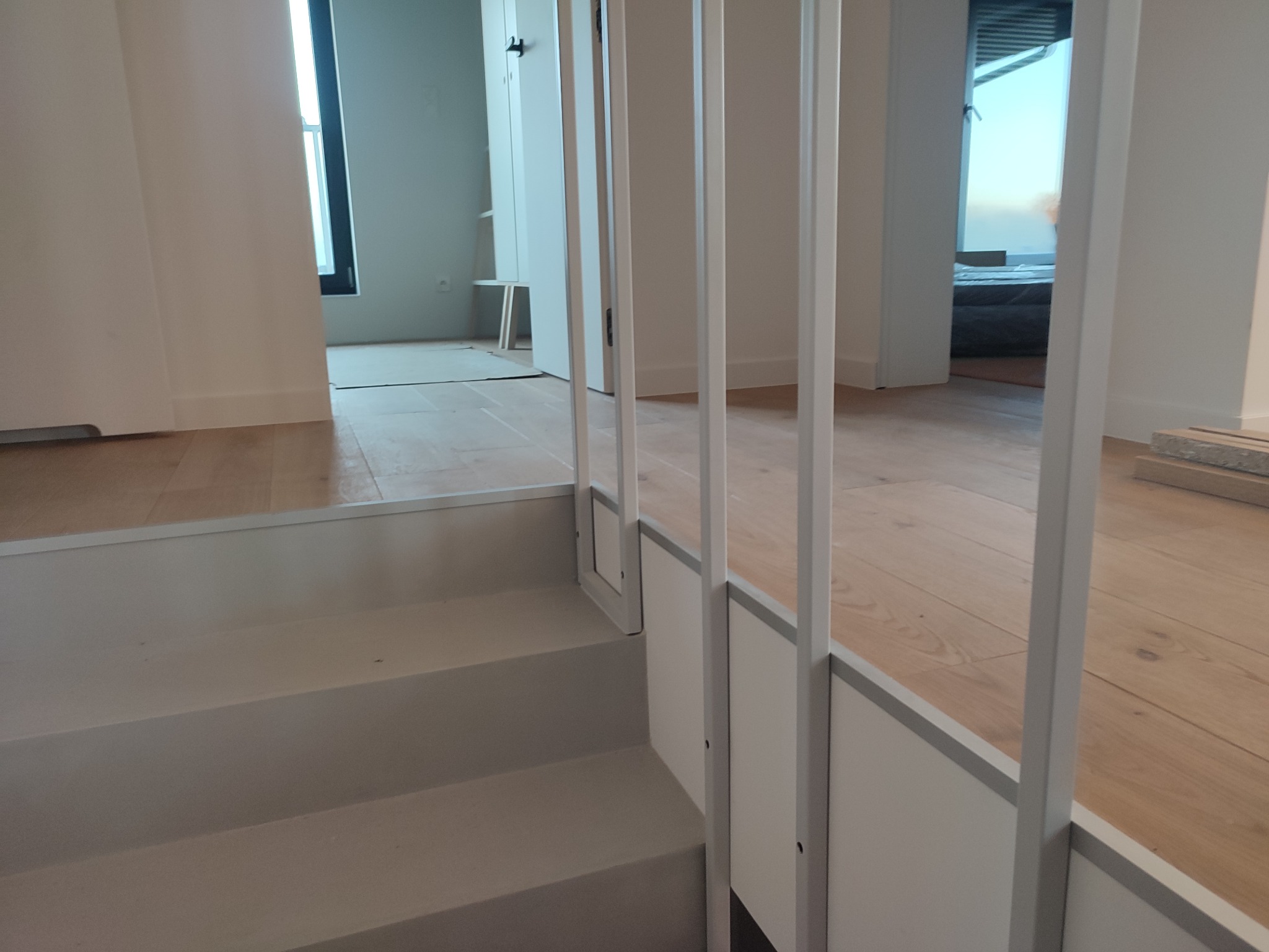 Nowoczesne schody wewnętrzne z białymi balustradami i drewnianą podłogą, widok z dołu, minimalistyczny design.